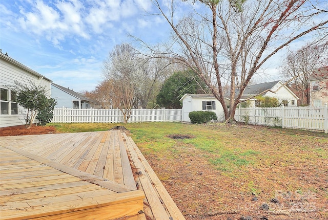 view of yard with an outbuilding, a wooden deck, a storage shed, and a fenced backyard