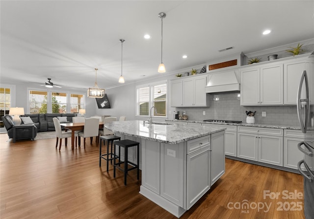 kitchen with custom range hood, visible vents, a wealth of natural light, and a sink