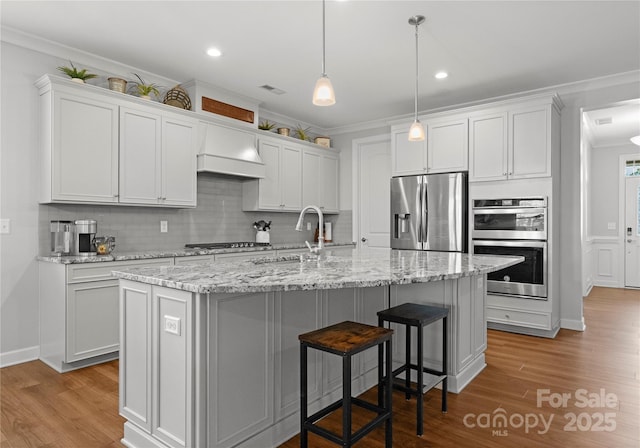 kitchen featuring premium range hood, wood finished floors, appliances with stainless steel finishes, and ornamental molding