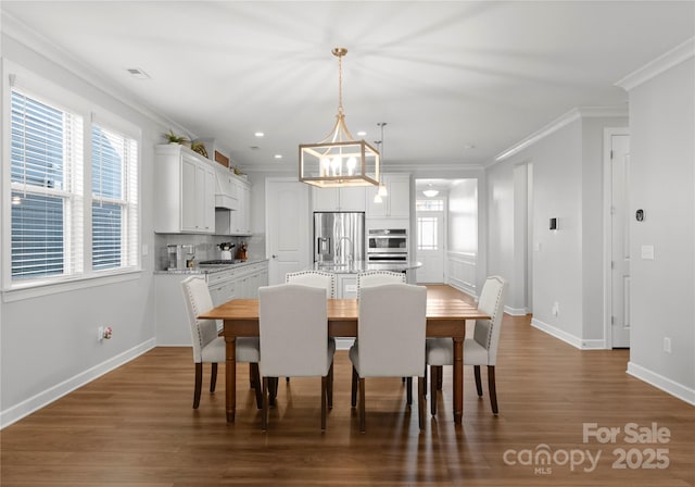 dining area featuring visible vents, crown molding, baseboards, and wood finished floors