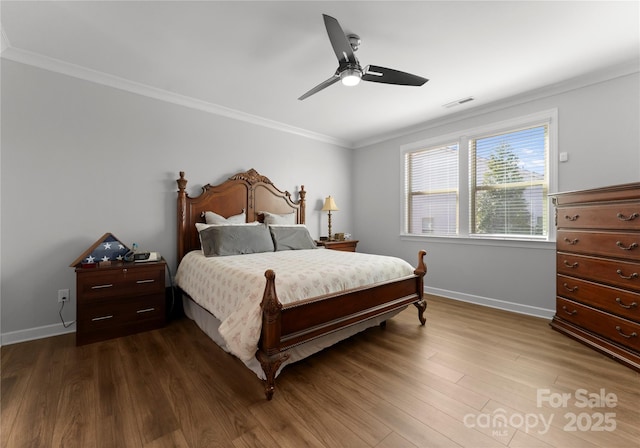 bedroom featuring visible vents, baseboards, ornamental molding, wood finished floors, and a ceiling fan