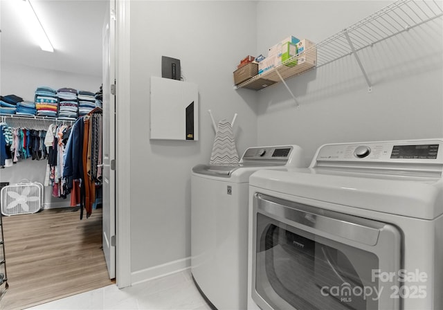 laundry room with laundry area, light tile patterned floors, baseboards, and independent washer and dryer