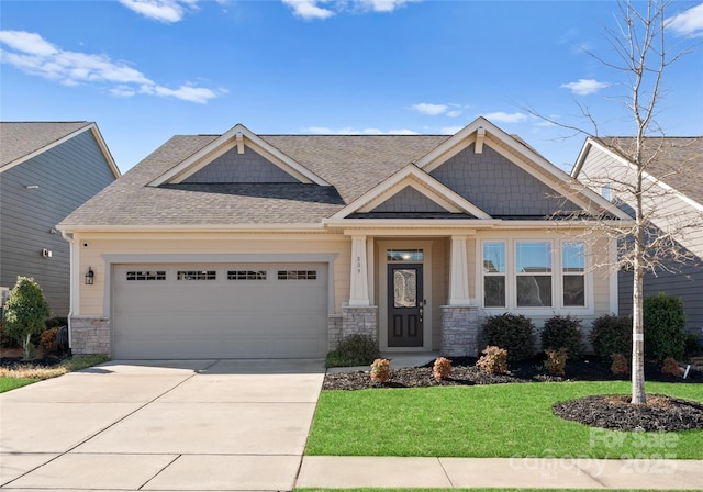 craftsman inspired home featuring a front lawn, concrete driveway, roof with shingles, stone siding, and an attached garage