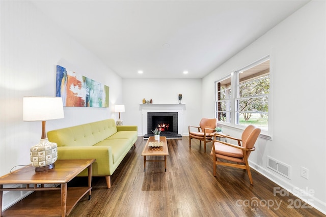 living area with recessed lighting, visible vents, a brick fireplace, wood finished floors, and baseboards