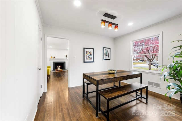 dining space with visible vents, dark wood finished floors, crown molding, a fireplace, and recessed lighting