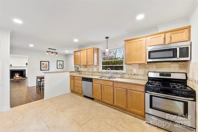 kitchen with crown molding, tasteful backsplash, appliances with stainless steel finishes, a sink, and a lit fireplace