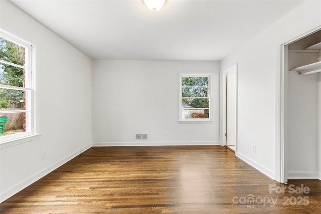 unfurnished bedroom featuring wood finished floors, visible vents, and baseboards