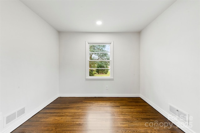 unfurnished room with baseboards, visible vents, and wood finished floors