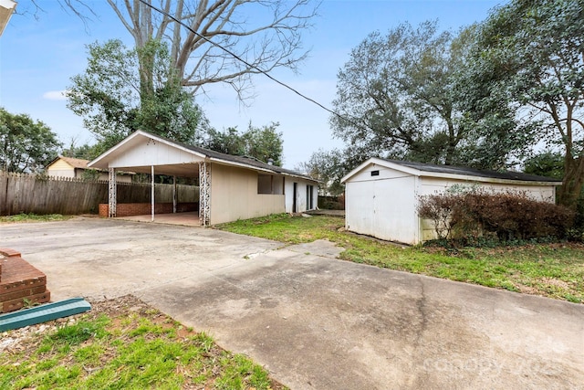 exterior space with driveway, fence, an attached carport, and an outbuilding