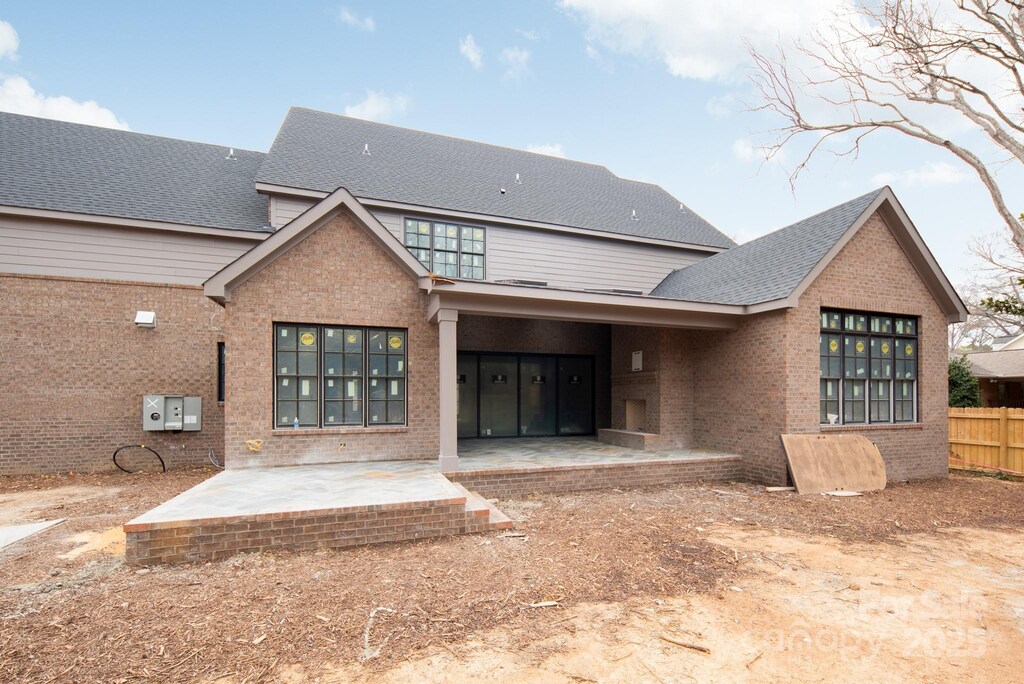 back of house with a shingled roof, a patio area, brick siding, and fence