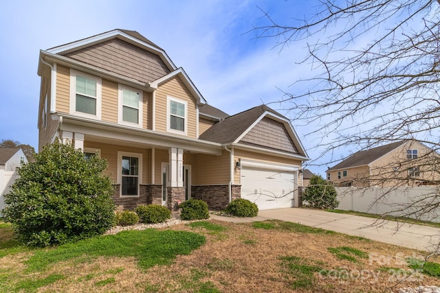 craftsman inspired home featuring stone siding, fence, concrete driveway, a front yard, and an attached garage