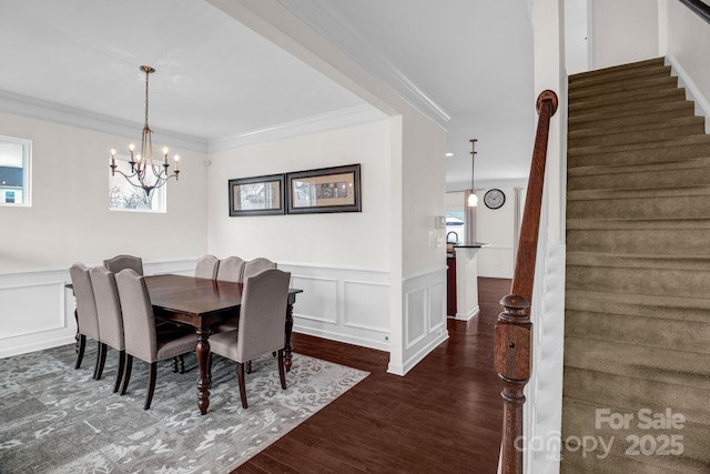 dining room featuring stairs, ornamental molding, a wealth of natural light, wood finished floors, and a decorative wall