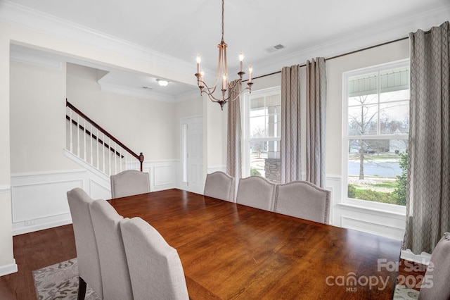 dining area featuring a wealth of natural light, an inviting chandelier, wood finished floors, and stairs