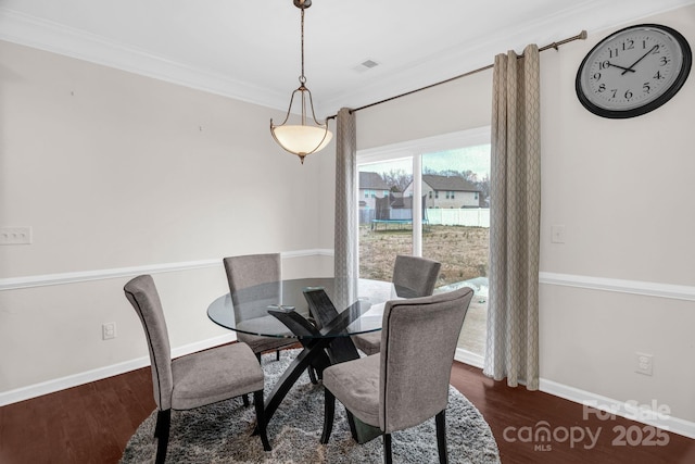 dining space featuring visible vents, crown molding, baseboards, and wood finished floors