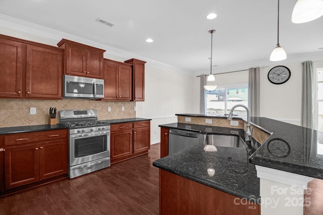 kitchen with dark wood-style flooring, a large island with sink, ornamental molding, a sink, and appliances with stainless steel finishes