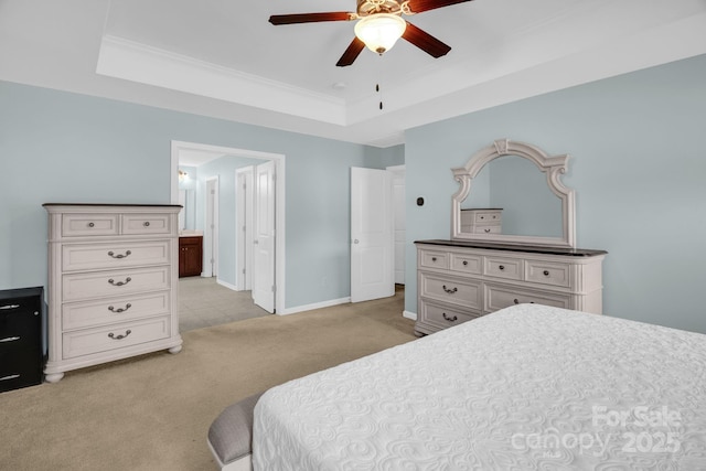 bedroom featuring light carpet, a raised ceiling, ornamental molding, ensuite bathroom, and baseboards