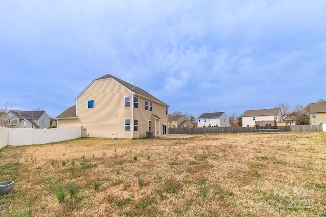 view of yard featuring a residential view, central AC unit, and a fenced backyard