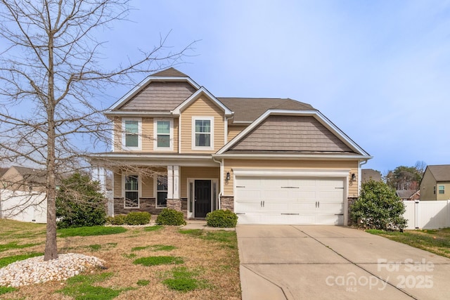 craftsman inspired home featuring fence, covered porch, a garage, stone siding, and driveway