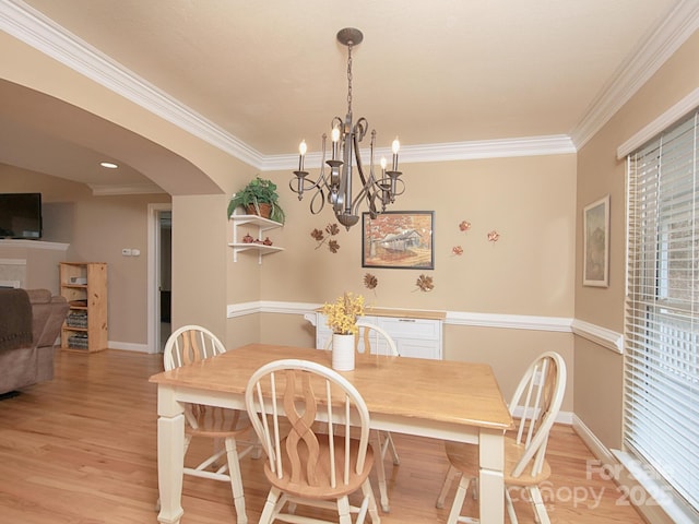 dining area with arched walkways, ornamental molding, baseboards, and light wood-style floors