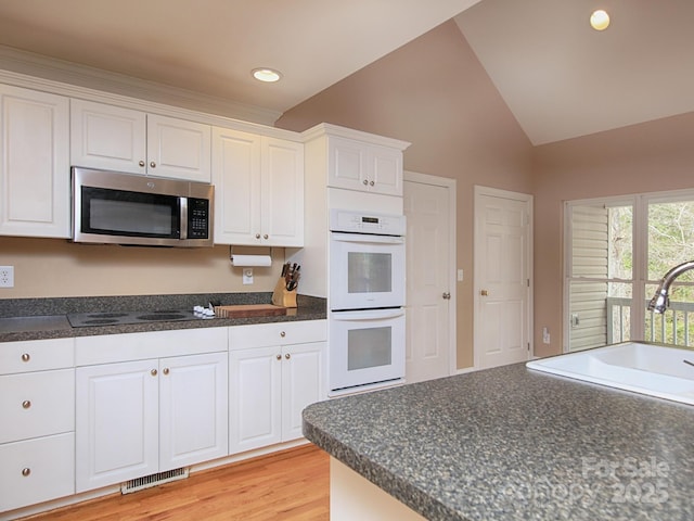 kitchen featuring double oven, electric stovetop, a sink, stainless steel microwave, and dark countertops