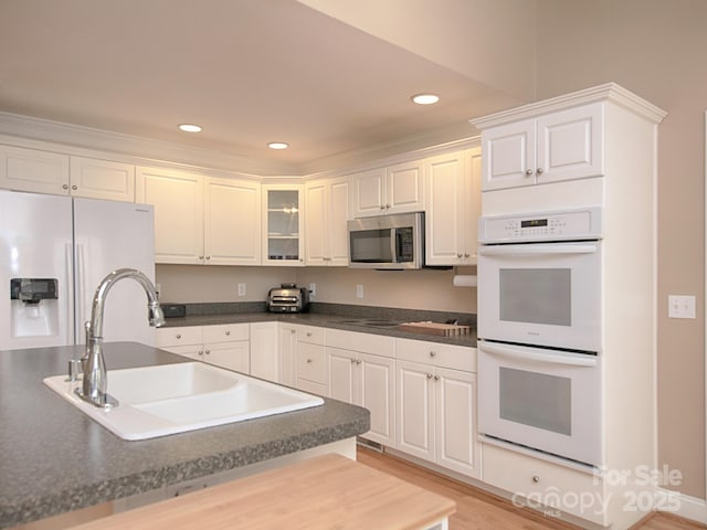 kitchen with stainless steel appliances, dark countertops, white cabinetry, and a sink