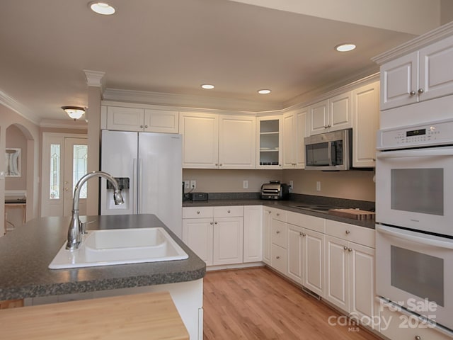 kitchen featuring appliances with stainless steel finishes, dark countertops, a sink, and crown molding