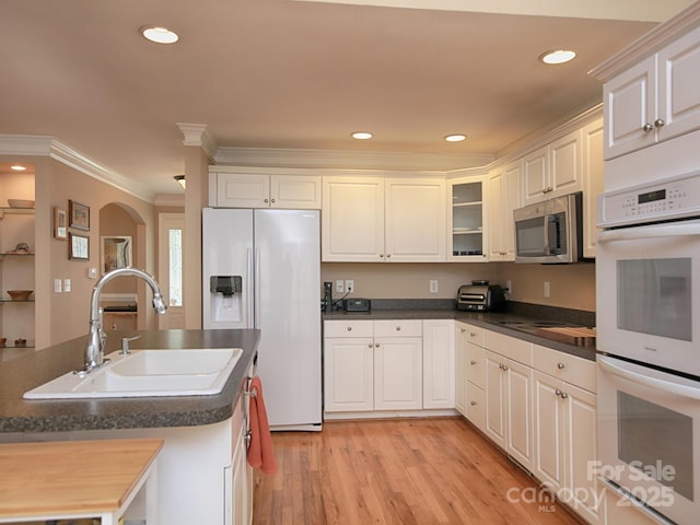 kitchen featuring crown molding, stainless steel microwave, double oven, fridge with ice dispenser, and a sink