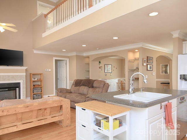 living room with light wood-style floors, ornamental molding, a tiled fireplace, and recessed lighting