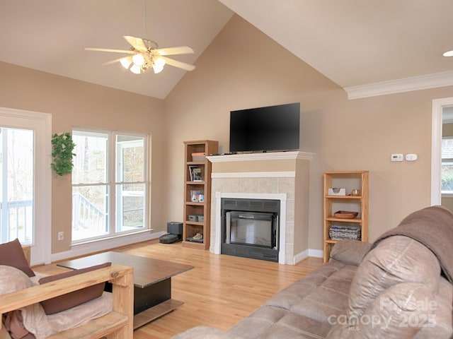 living area featuring baseboards, wood finished floors, vaulted ceiling, crown molding, and a fireplace