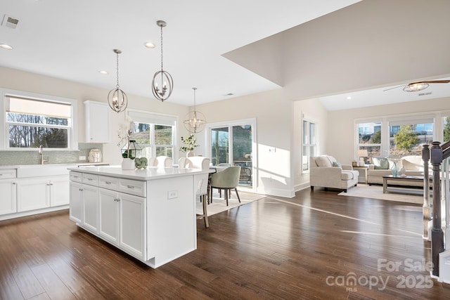 kitchen featuring dark wood-type flooring, a notable chandelier, open floor plan, a center island, and light countertops