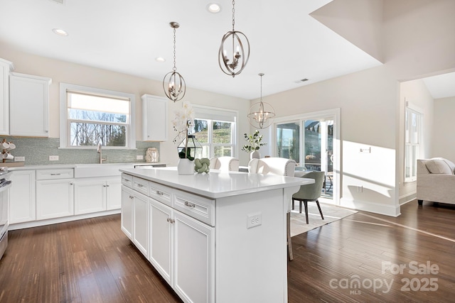 kitchen featuring dark wood-type flooring, a notable chandelier, backsplash, and a sink