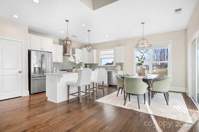 kitchen with a kitchen breakfast bar, dark wood-style floors, appliances with stainless steel finishes, and a kitchen island