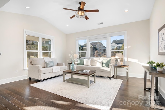 living area featuring a wealth of natural light, dark wood-type flooring, baseboards, and vaulted ceiling