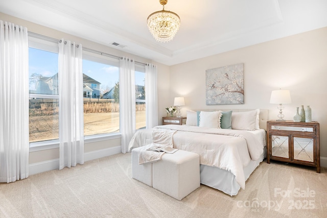 carpeted bedroom with a tray ceiling, a notable chandelier, baseboards, and visible vents