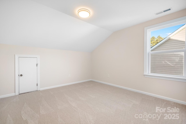 bonus room with visible vents, lofted ceiling, light colored carpet, and baseboards