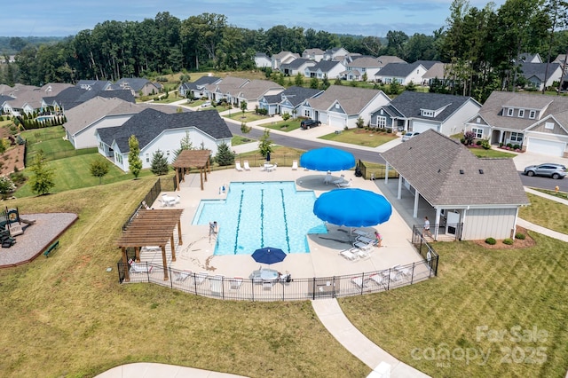 community pool featuring a residential view, a water slide, and fence