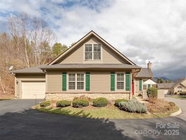 view of front of home featuring aphalt driveway, stone siding, a shingled roof, and a garage