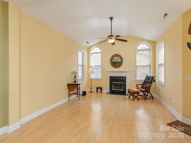 living area with a healthy amount of sunlight, a premium fireplace, visible vents, and wood finished floors