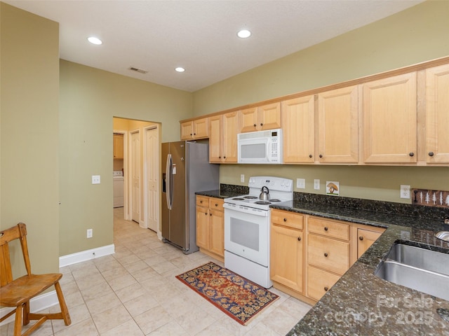 kitchen with light brown cabinetry, white appliances, and a sink