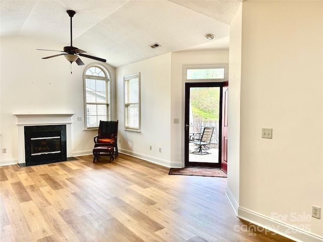 entryway with vaulted ceiling, visible vents, a ceiling fan, light wood-style floors, and a premium fireplace