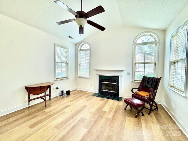 sitting room featuring a fireplace, vaulted ceiling, wood finished floors, and plenty of natural light