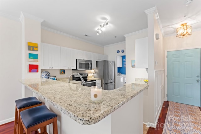 kitchen with dark wood-style flooring, light stone countertops, a peninsula, and appliances with stainless steel finishes