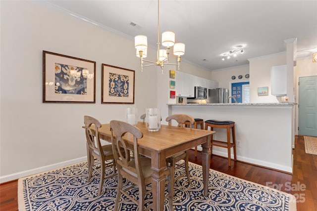 dining space with dark wood-type flooring, a notable chandelier, visible vents, and crown molding