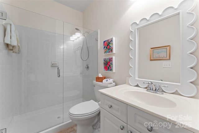full bathroom featuring a shower stall, toilet, and vanity