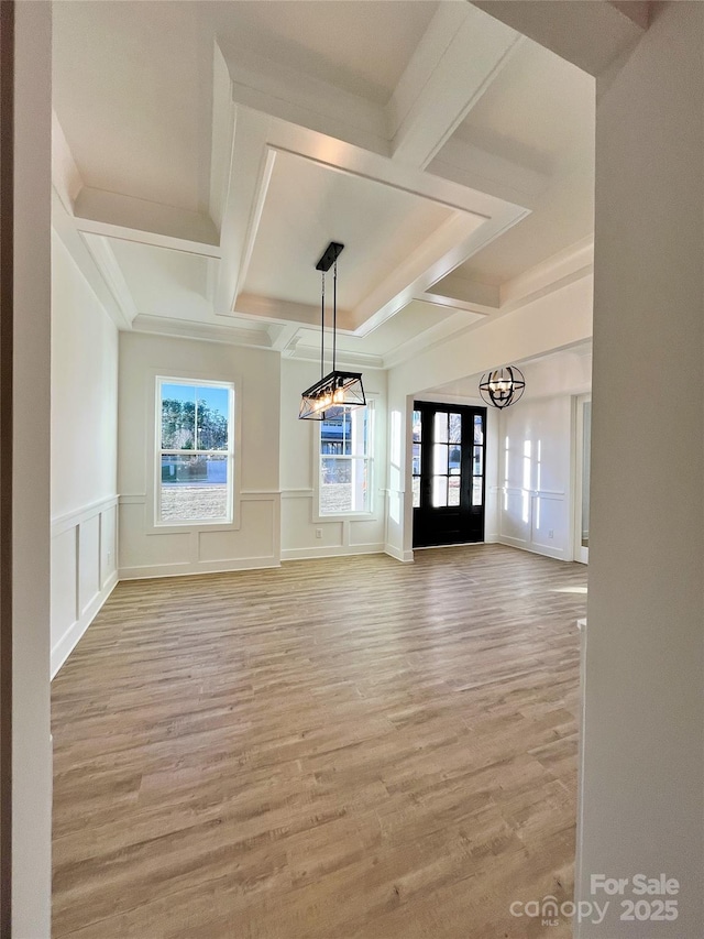 spare room with coffered ceiling, a wainscoted wall, light wood-style floors, a decorative wall, and beam ceiling