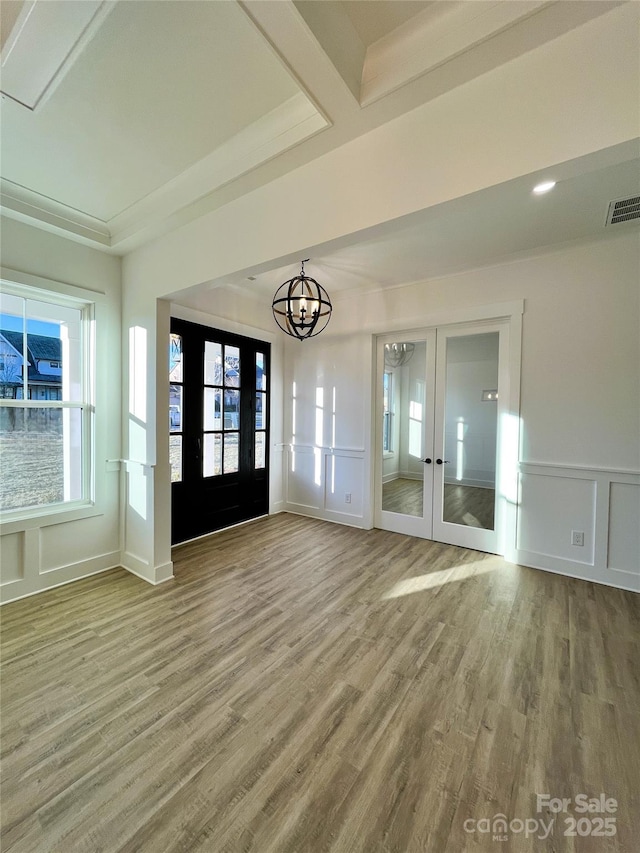 interior space featuring a healthy amount of sunlight, an inviting chandelier, visible vents, and french doors