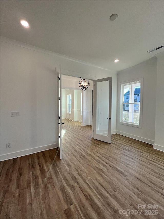 spare room featuring wood finished floors, visible vents, and baseboards