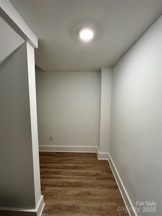 spare room featuring dark wood-style flooring and baseboards