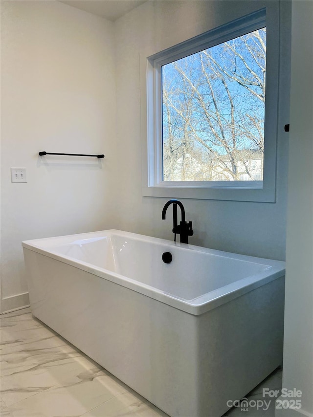 bathroom with a freestanding tub and marble finish floor