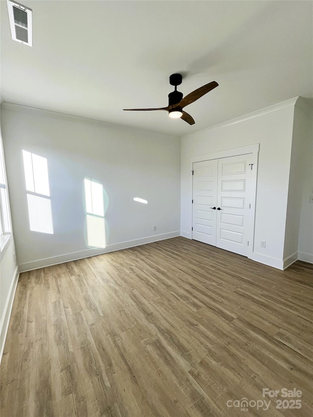 unfurnished bedroom featuring a closet, visible vents, baseboards, and wood finished floors